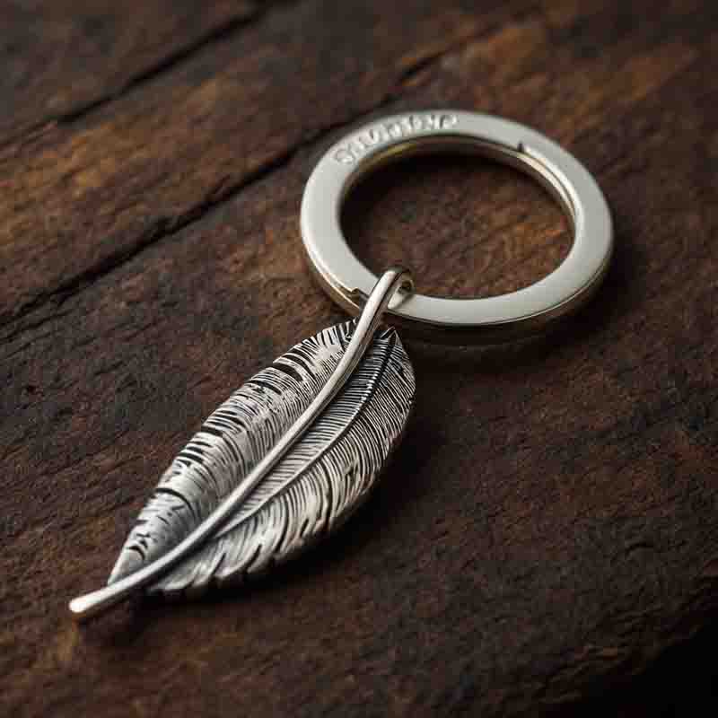 A silver feather keychain elegantly rests on a rustic wooden table, showcasing its intricate design and shine.